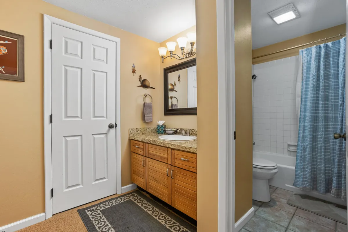 A modern bathroom with a wide vanity, ample counter space, a large wall mirror, a shower area, and decorative wall art. The room is bright and organized, ideal for shared use and privacy.