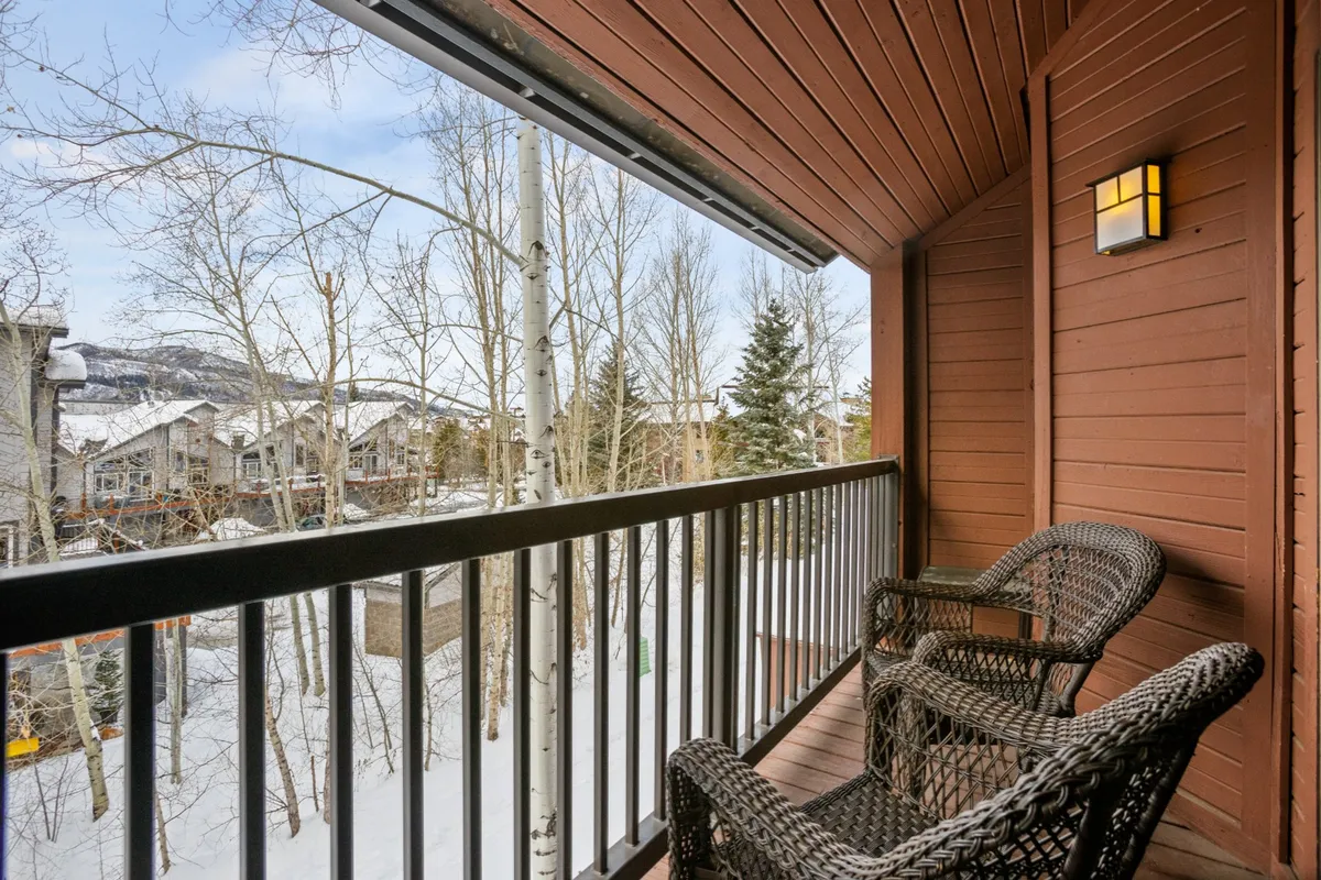 A peaceful balcony scene, featuring woven chairs overlooking a snow-covered landscape, distant mountains, and bare winter trees. The setting is tranquil and reflective, inviting guests to relax and take in the mountain views.