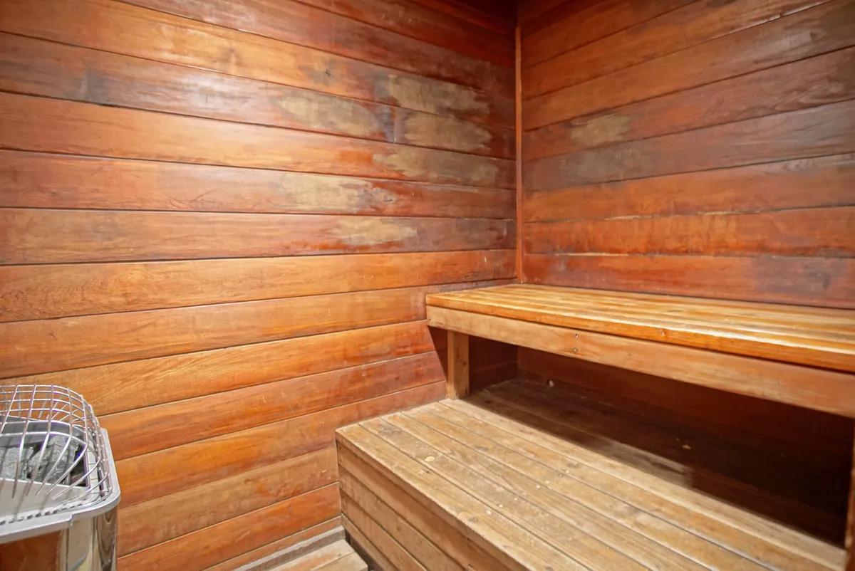 A tranquil interior space featuring wooden benches and walls with a central heating element, representing the property's sauna. The mood is calm, inviting guests to unwind and rejuvenate indoors.