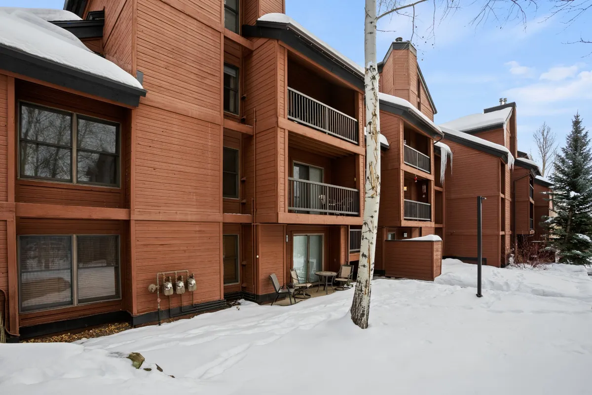 The image shows the exterior of Timber Run with its signature wooden architecture, snow-covered ground, and balconies. The setting conveys peaceful winter scenery and hints at the inviting balconies where guests can enjoy the crisp mountain air.